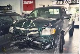 Green Toyota pickup with front-end crash damage, before repair